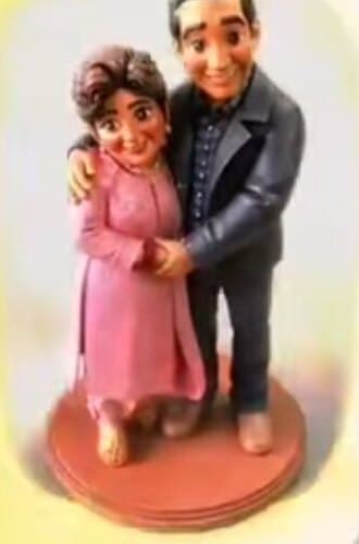 3D printed couple miniature of a woman in a pink kurta and a man in a grey jacket on a wooden base